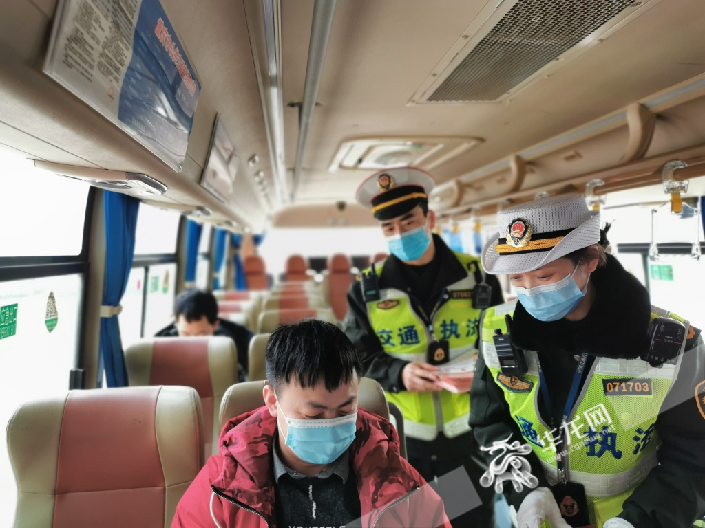 执法队员在大巴车上向乘客发放交通安全宣传资料。华龙网-新重庆客户端记者 刘艳 摄