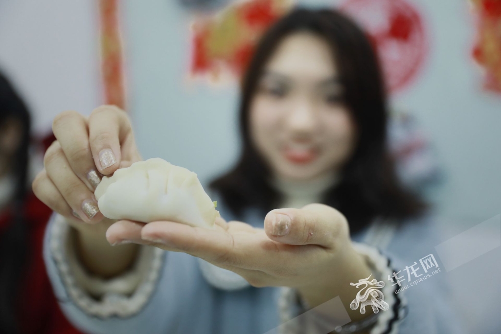 一名学生开心的展示自己包的饺子。华龙网-新重庆客户端 谢鹏 摄