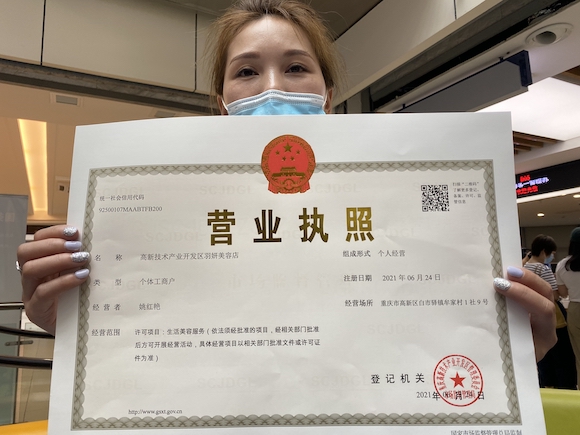 市民在重庆高新区领取了全国首张整合卫生许可信息的“一码通行”营业执照。华龙网-新重庆客户端 记者 罗杰 摄