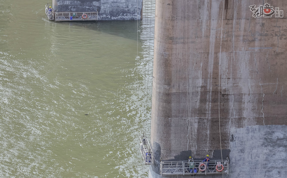 由于风吹日晒，牛角沱嘉陵江大桥的桥墩（台）出现了大小不一的各种裂缝，因此工人们还要从上百米高的桥面板上乘坐吊车下到桥墩处补修。