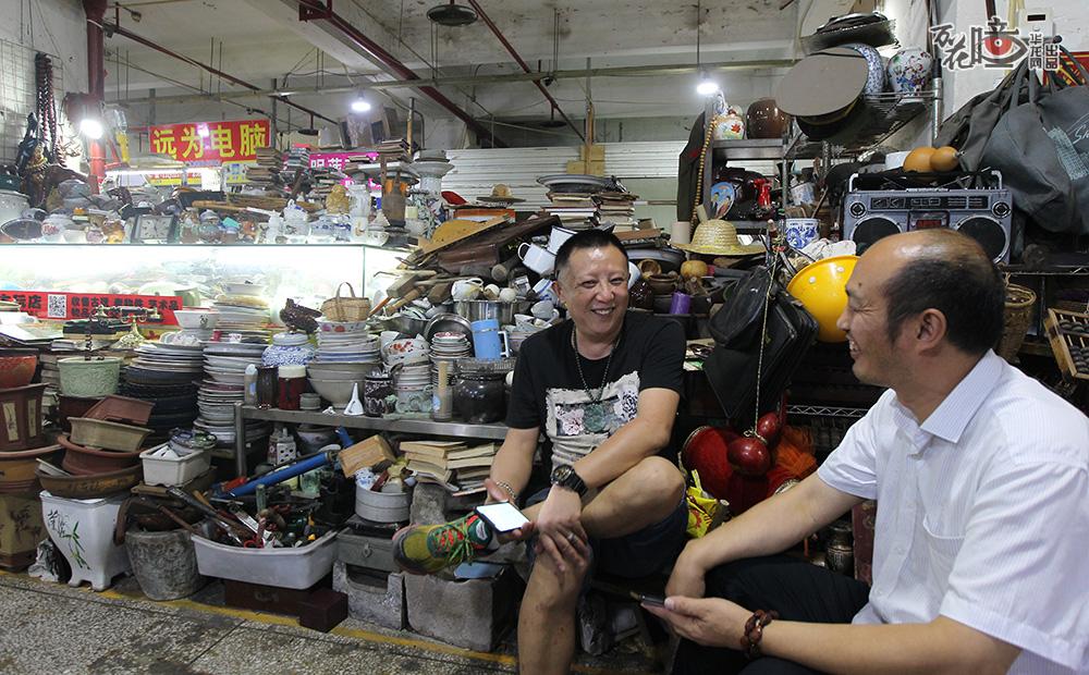 刘正东（中）在和老顾客聊天，他的铺位在市场中间，多而杂。他骄傲的说好多剧组都找他帮忙攒道具。