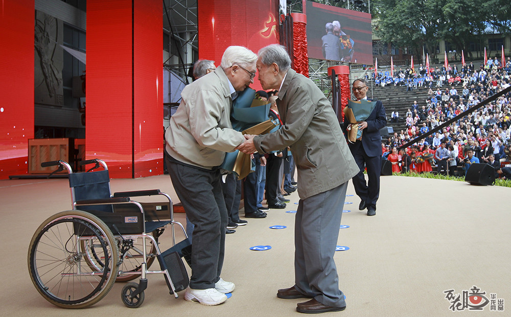 10月12日，重庆大学90周年校庆纪念大会上，两位老人的照片在网上刷屏。95岁学生代表丁传培（右）向94岁老师代表许香穗献花。这一幕，感动。华龙网—新重庆客户端 记者 张质 摄