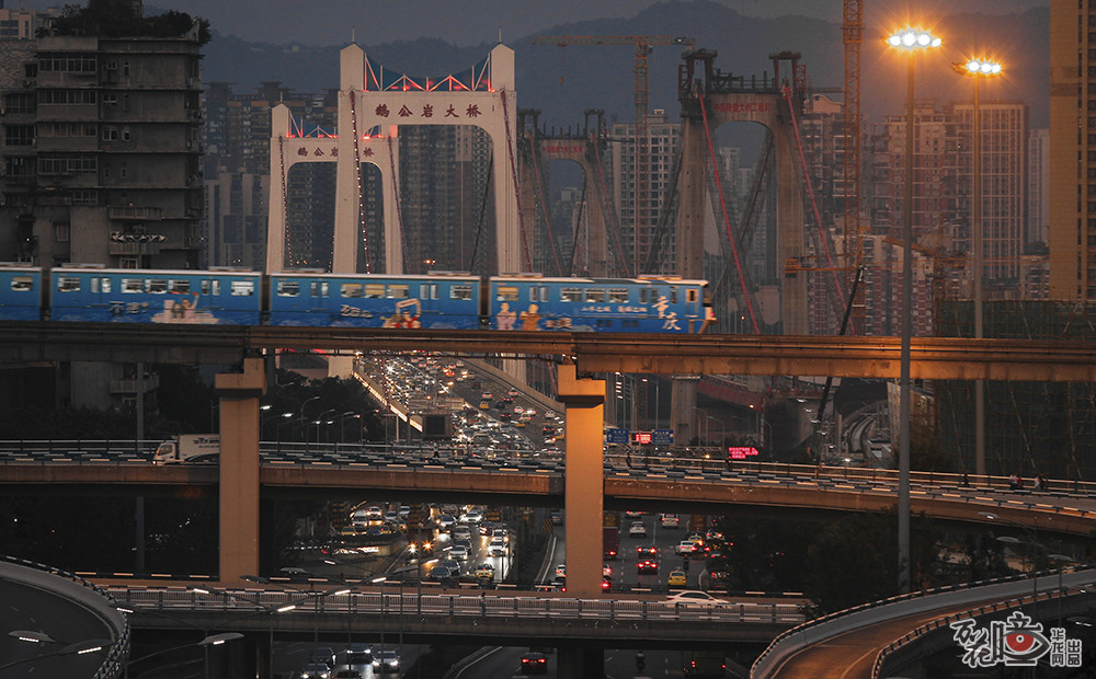 7月25日，一列单轨列车从谢家湾立交驶过，身后是新晋的热门城市风光打卡点鹅公岩双桥。华龙网—新重庆客户端 记者 张质 摄