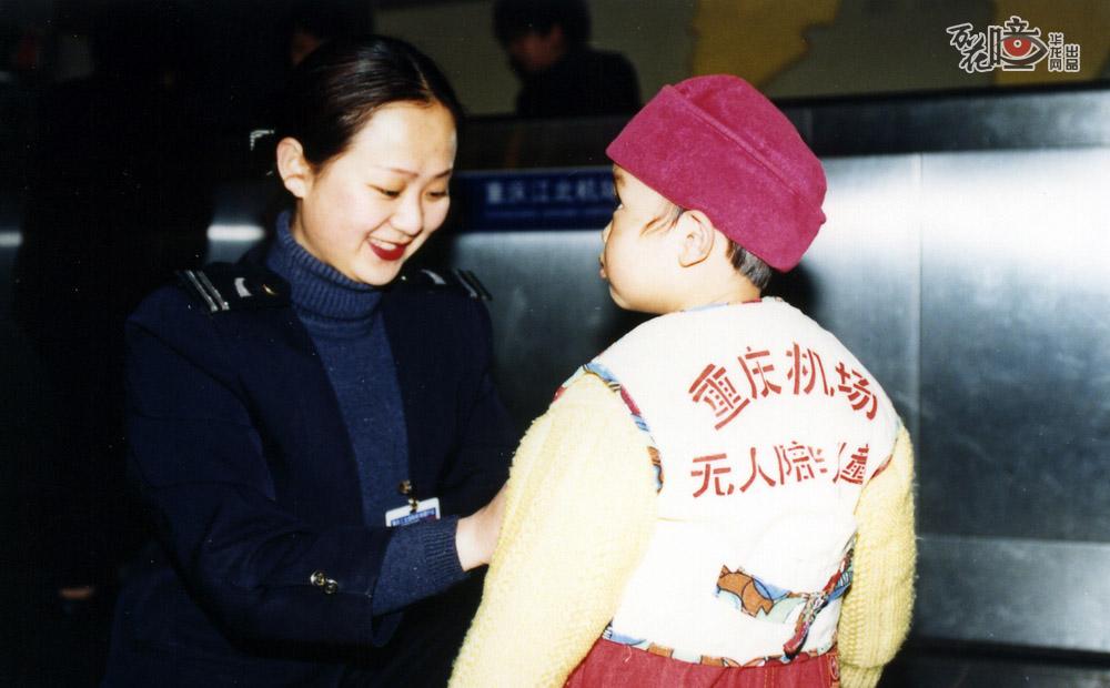 为了方便出行的旅客，早在投运不久，江北机场就推出了无人陪伴儿童服务。机场工作人员正在为一名儿童旅客穿上无人陪伴标识的马甲。