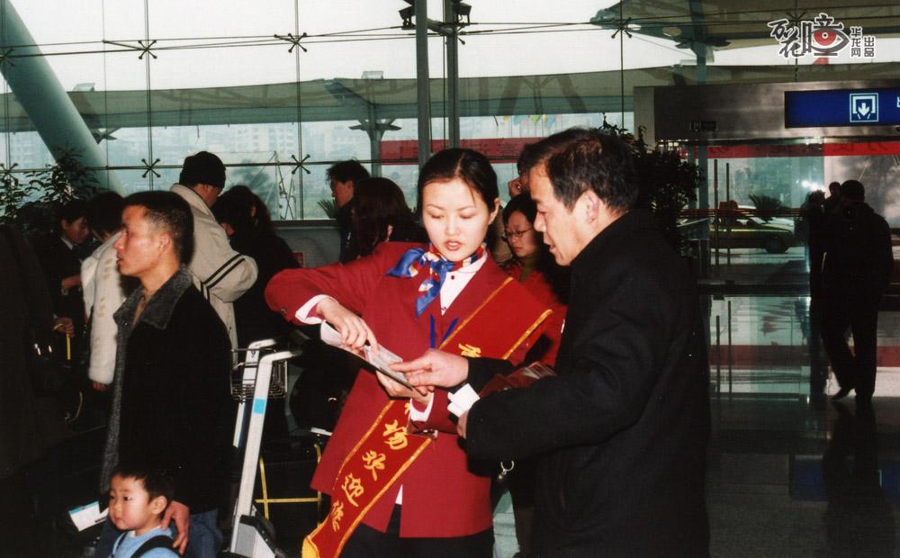 2004年，江北国际机场T2B航站楼投用后，一名志愿者正在为旅客提供问询服务。