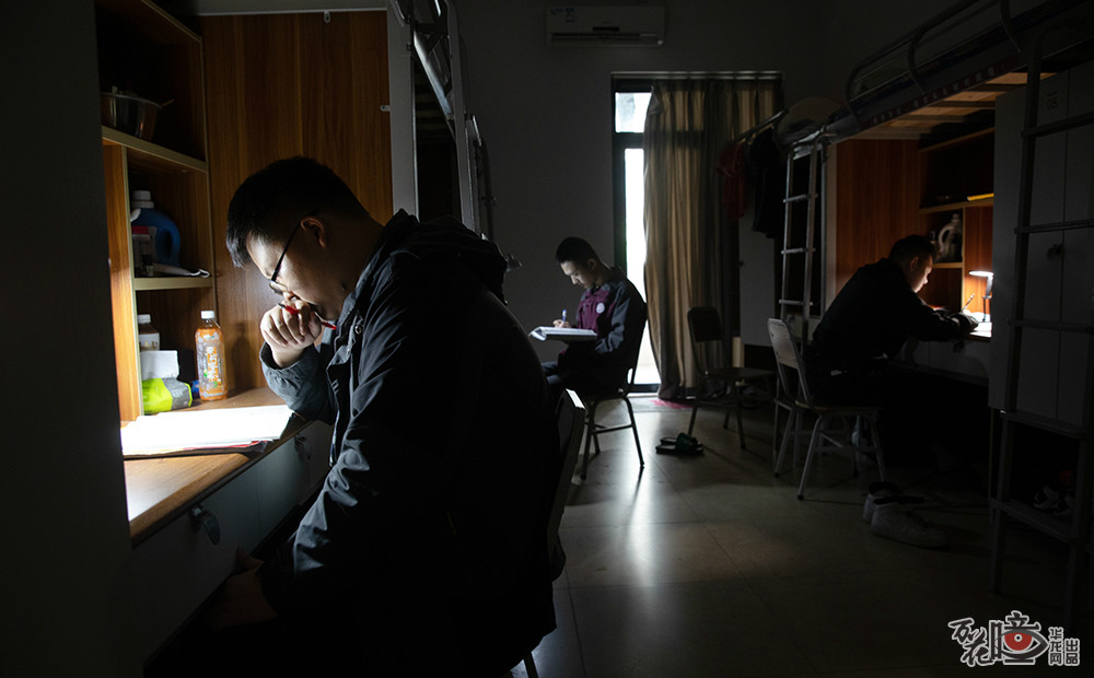 在杨家坪中学彩云湖校区，高三22班210宿舍三个男生为了不打扰午休的室友，拉上窗帘，开着台灯学习。