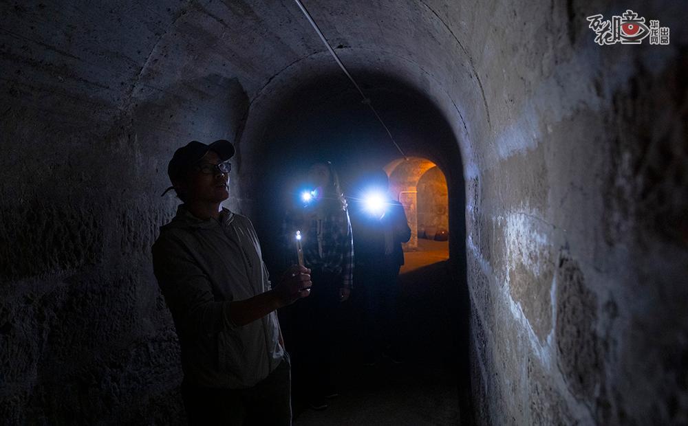 防空洞内，还有一段未开发成书屋。军哥带着两位浙江游客一起游览向她们讲解重庆防空洞的历史。